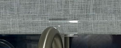 Clear pull tab on the bottom rail of a cordless gray linen look roller shade
